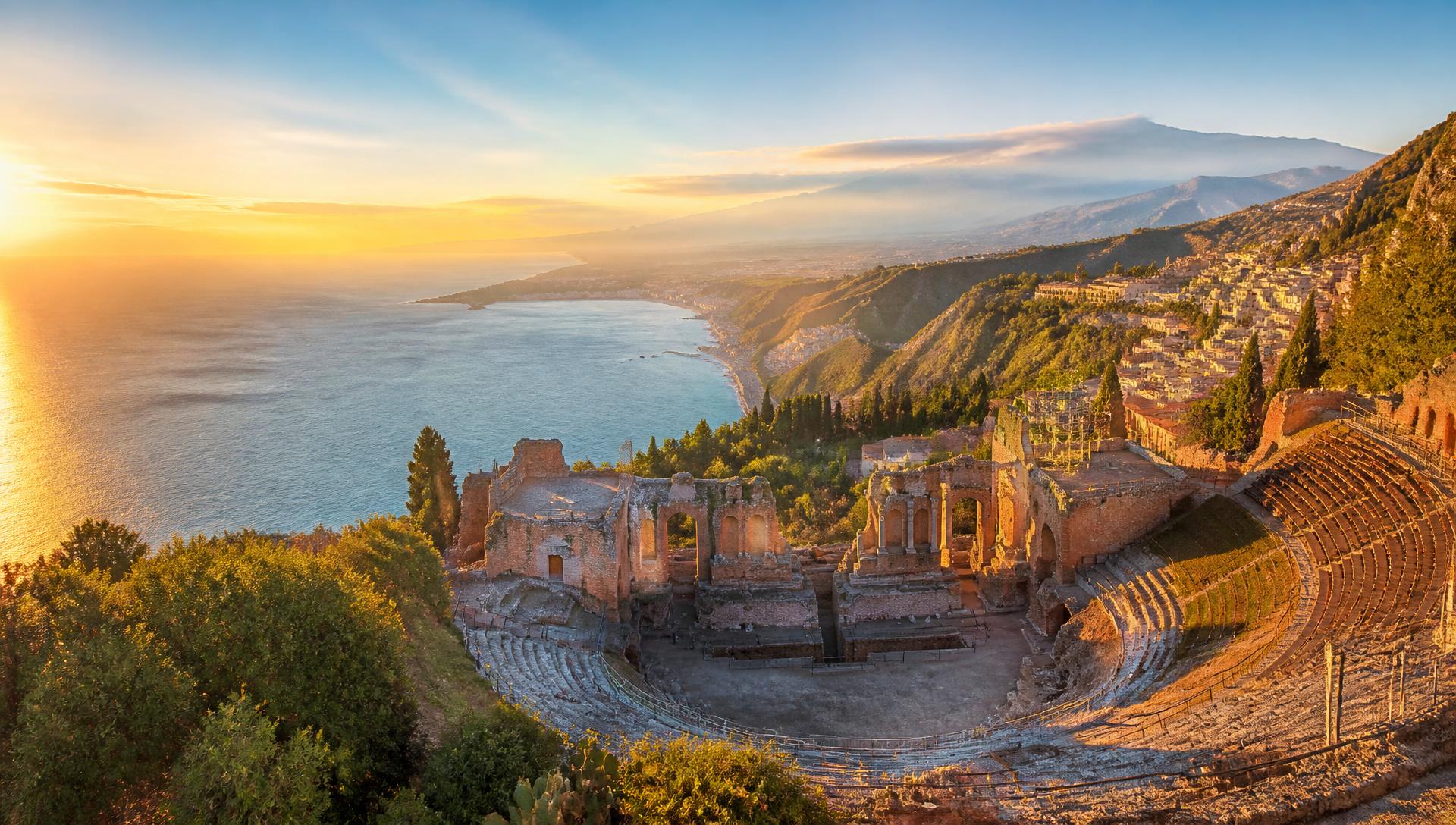 Taormina ancient Greek theater overlooking turquoise Ionian sea at golden sunset